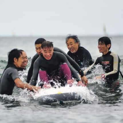 サーフィンが大好きな川名さん（認知症当事者）と一緒にサーフィンを楽しむナミニケーションズのみなさん（福祉タイムズ2023年6月号）